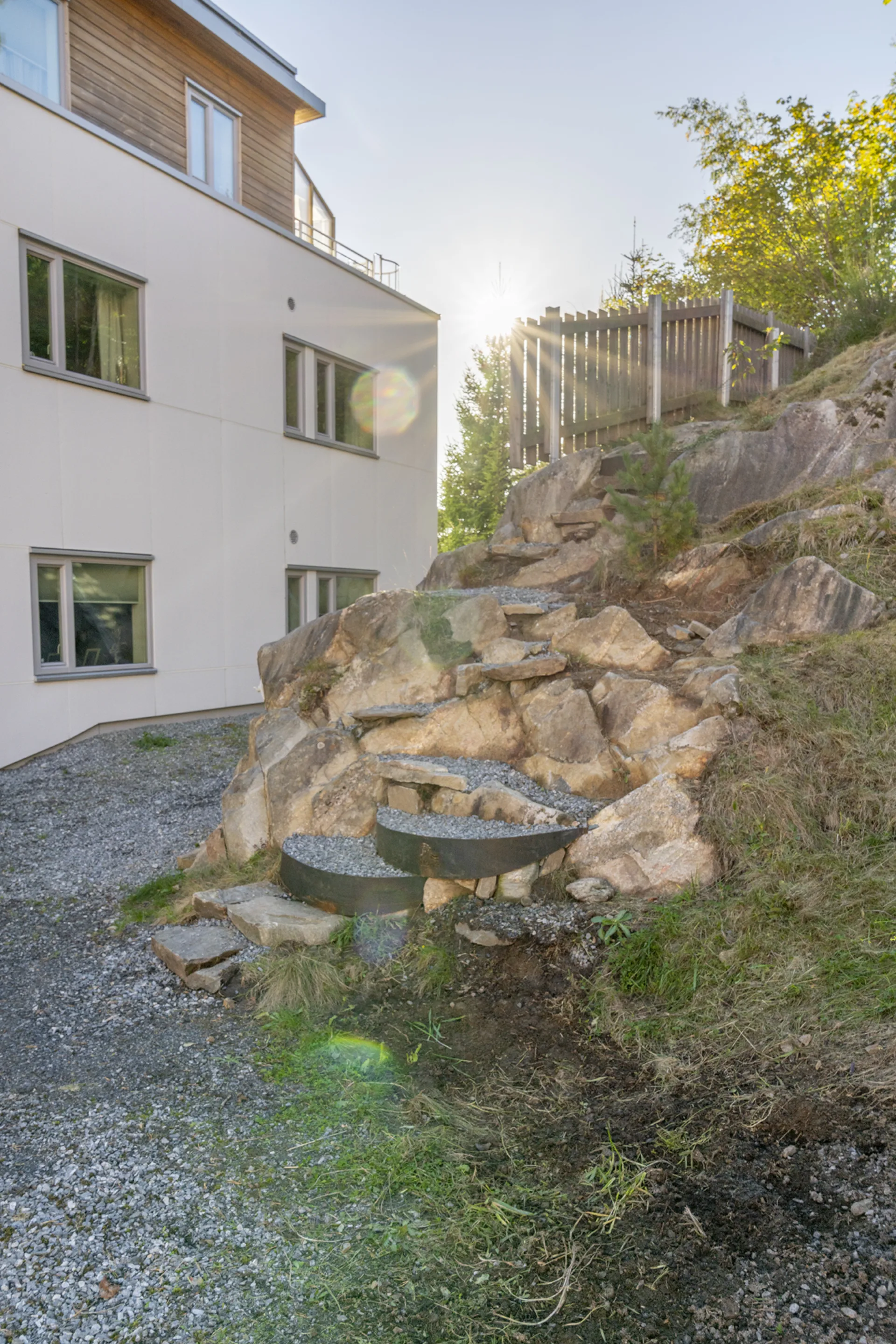 Nybygget trapp ute, fotografert i motlys med boligblokken i bakgrunnen.